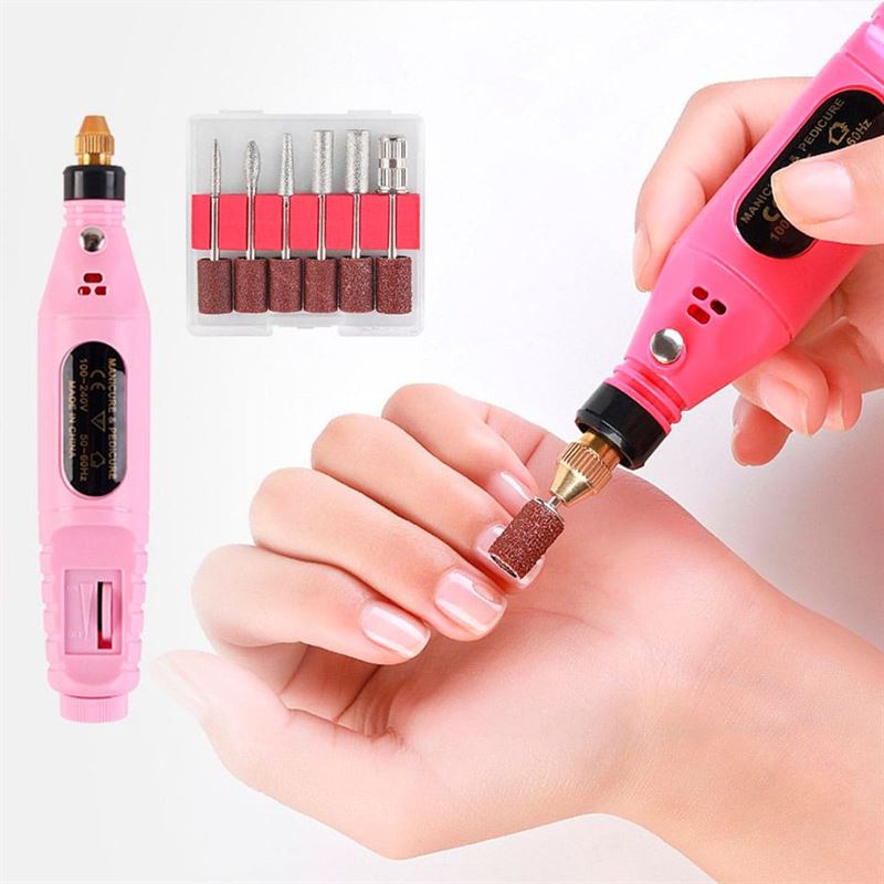 A person uses the Fashiongirl Electric Nail File 6-in-1 Manicure Set in pink on their fingernails, with included drill bits and sanding bands displayed beside the tool.