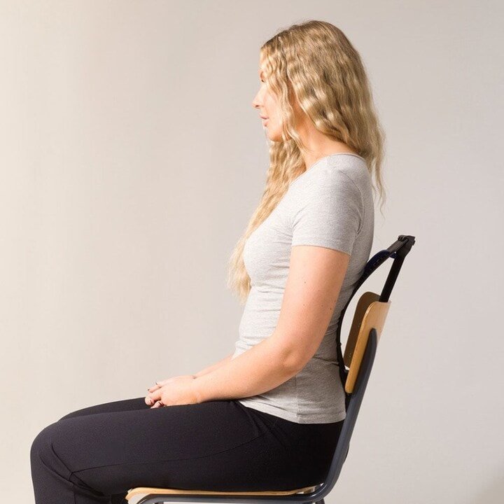 A woman with long blonde hair sits straight on a chair, using the Fashiongirl Pro Back Stretcher for posture correction and pain relief, demonstrating its effectiveness against a plain light background.