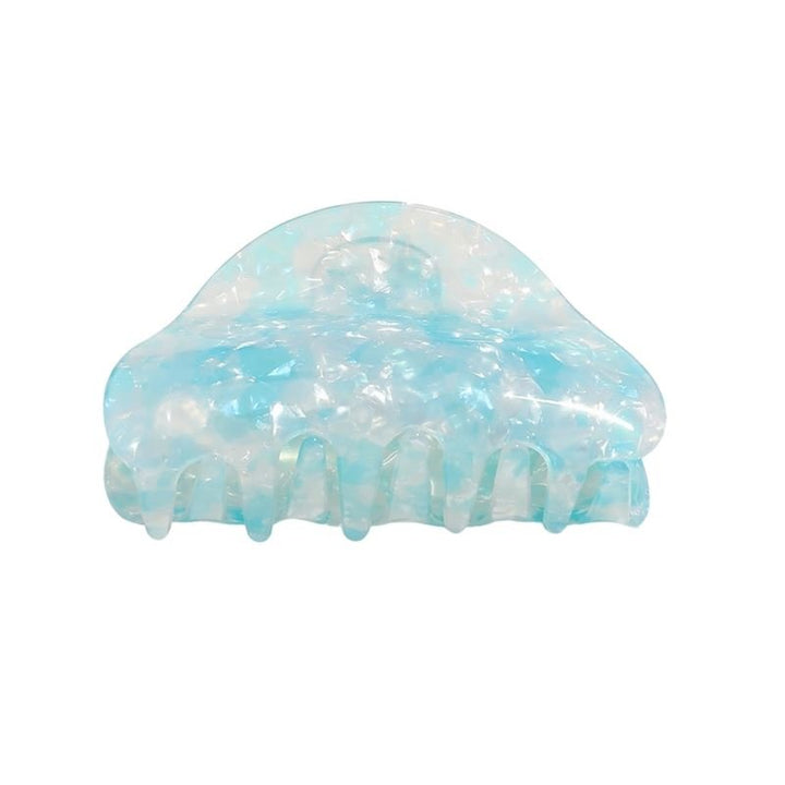 The SOHO Cleo Hair Claw - Crystal Blue by SOHO features a translucent blue and white marble pattern, a curved top, and interlocking teeth to hold hair securely in place.
