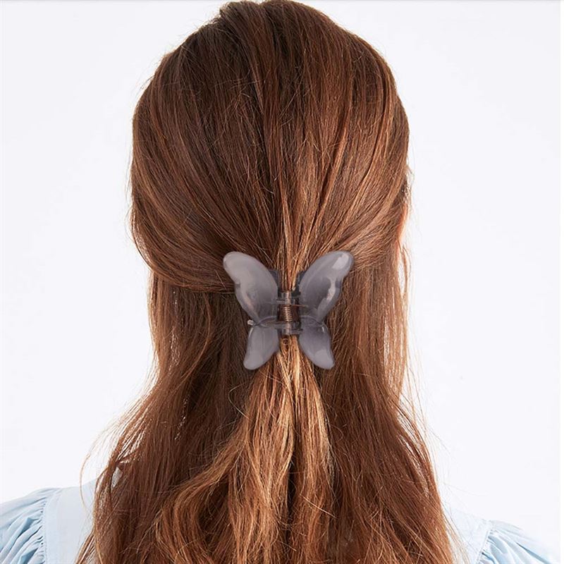 A person with long brown hair, seen from the back in a light blue top, showcases an adorable hairstyle secured with the SOHO Ella Hair Claw - Arctic by SOHO.