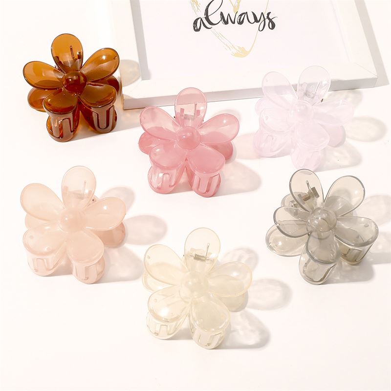 The SOHO Fiore Hair Claw in Pale Purple by SOHO is a stylish flower-shaped hair accessory, ideal for adding a chic touch to your look. Displayed on a white surface with a framed "always" print in the background.