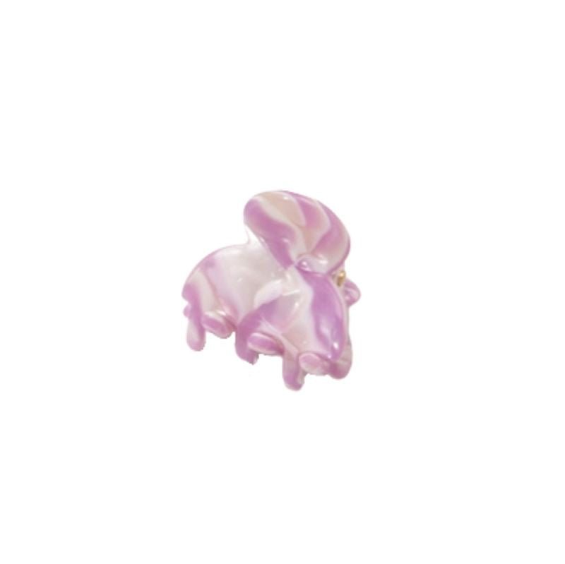 A SOHO Hara Mini Hair Claw in Periwinkle is displayed beside a small, glossy pink and white glass rabbit figurine, both shown against a plain white background.