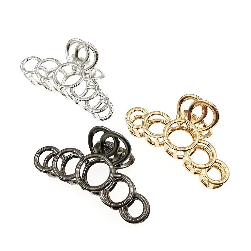 The SOHO Metal Hair Claw in Silver by SOHO features interlocking metal rings of varying sizes, designed to secure thick hair with stylish elegance, and is displayed on a white background.