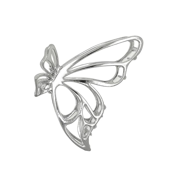The SOHO Nabi Hair Claw in silver by SOHO features a delicate, openwork butterfly design with thin, curved lines forming the wings and body, beautifully displayed against a white background.