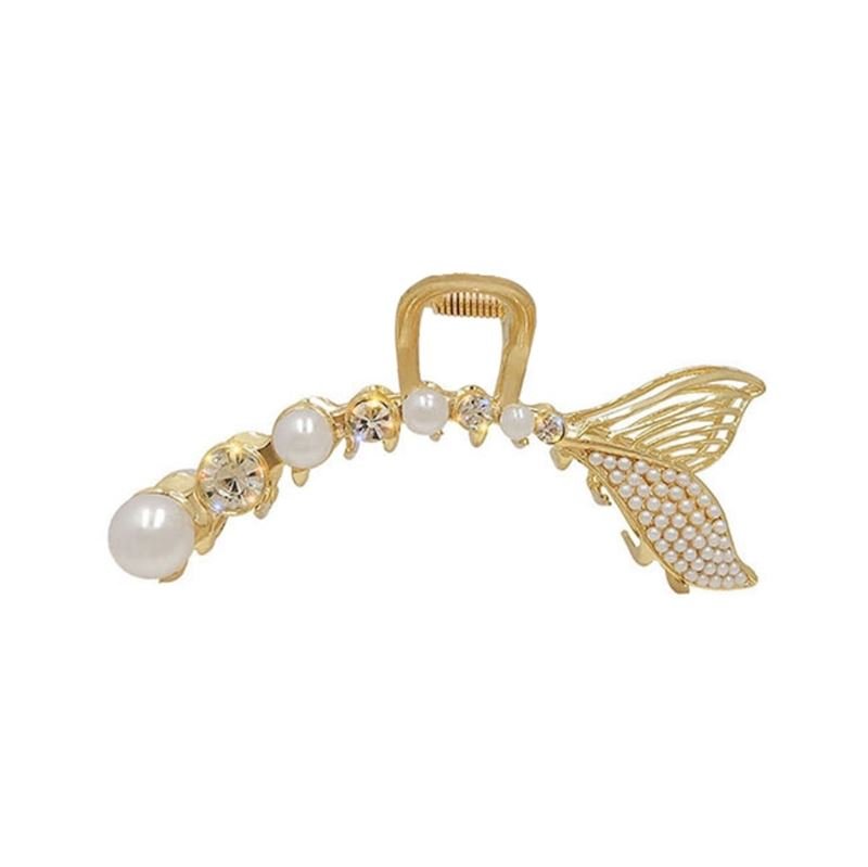 The SOHO Umi Hair Claw by SOHO features a gold fish-shaped design with pearls, rhinestones, and a textured tail fin for an enchanting mermaid-inspired look.