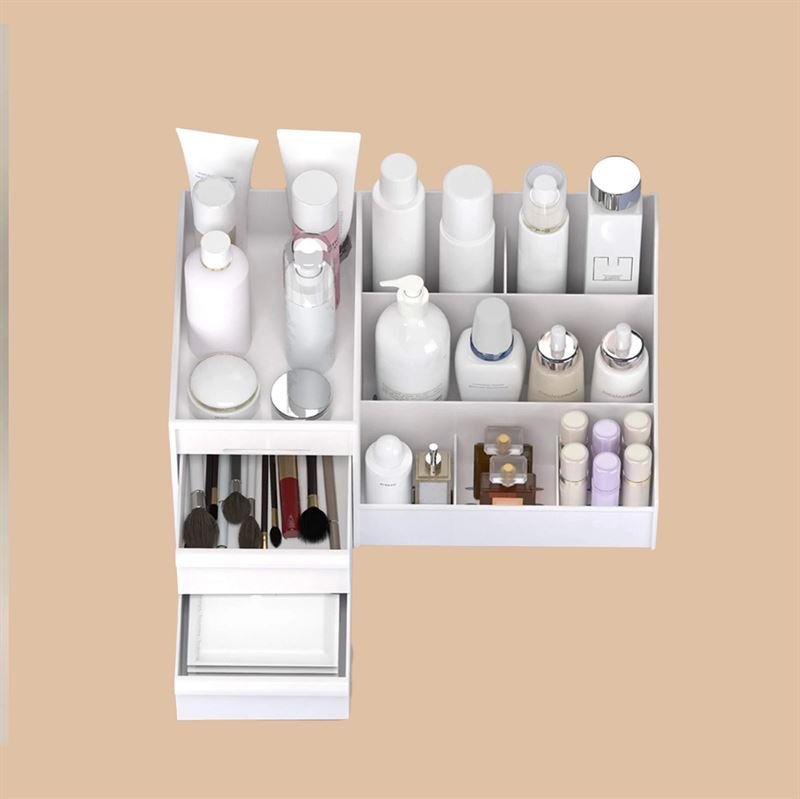The UNIQ Cosmetic Organiser with Two Drawers, White - P110 by UNIQ keeps bottles, jars, tubes, lipsticks, and brushes neatly arranged with multiple compartments against a beige background.