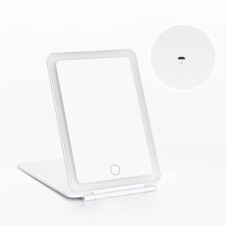 The UNIQ Foldable LED Makeup Mirror by UNIQ is a white, rechargeable mirror with a front touch button and visible charging port, propped open on a flat surface—ideal for travel or daily beauty routines.